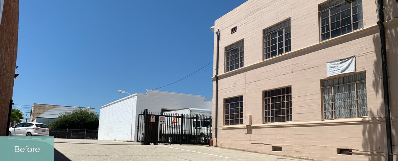Existing surface driveway, outside, white senior building, black iron fence