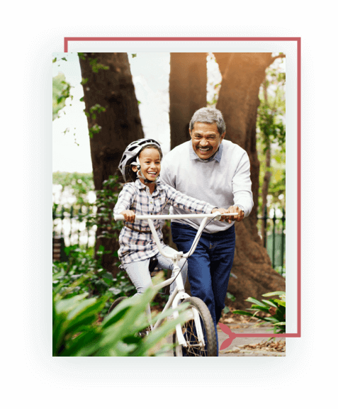 Smiling senior man helping girl ride a bike